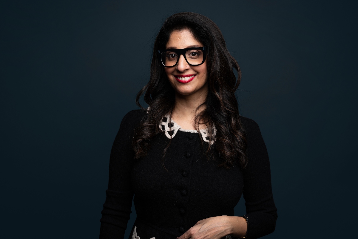 Komal standing smiling with glasses on